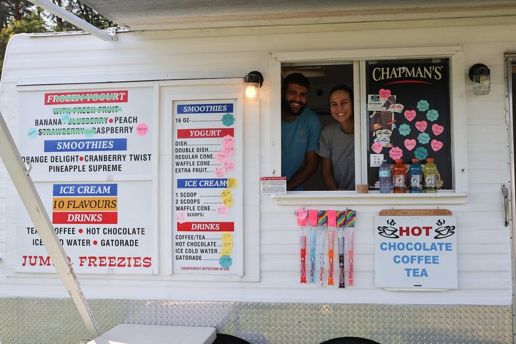 Chapman's food vendor booth at Beeton Fall Fair showing frozen yogurt, smoothies, ice cream, and drink menu with two smiling staff members